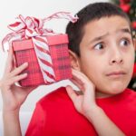 Shocked boy holding christmas gift | Stay at Home Mum.com.au