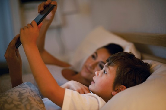 A mother reading a bedtime story to her son from a digital tablet