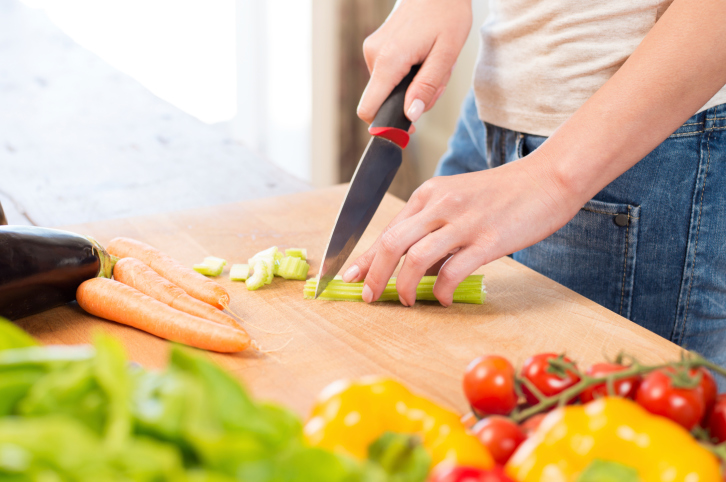 Woman Cutting Celery On Chopping Board